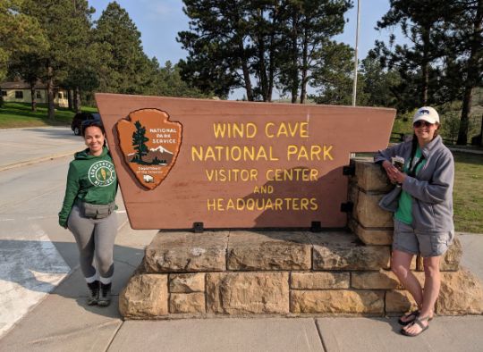 2 woman standing next to Wind Cave National Park Visitor Center