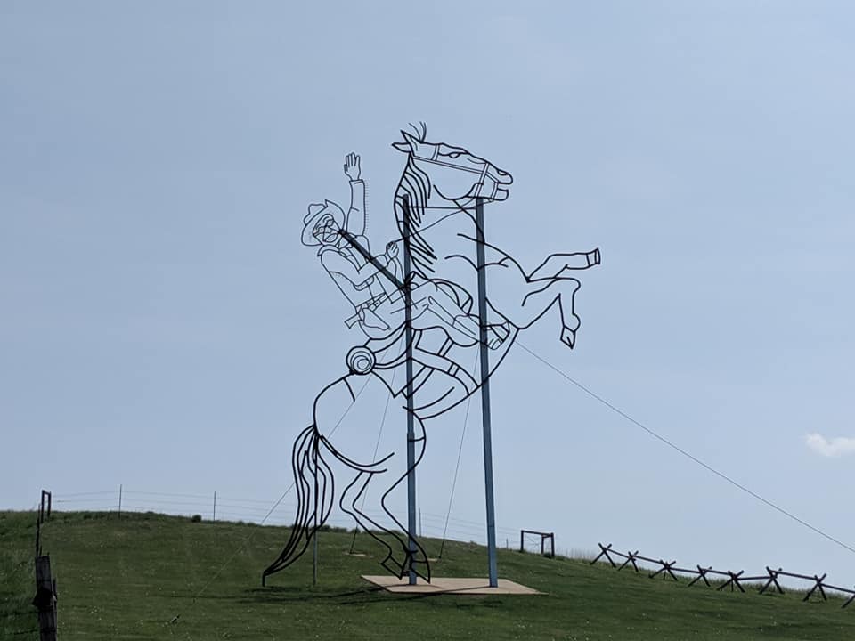 Silhouette of a giant cowboy on a horse that is reared back on its hind legs. This is a sculpture on a hill on the side of Regent Enchanted Highway.