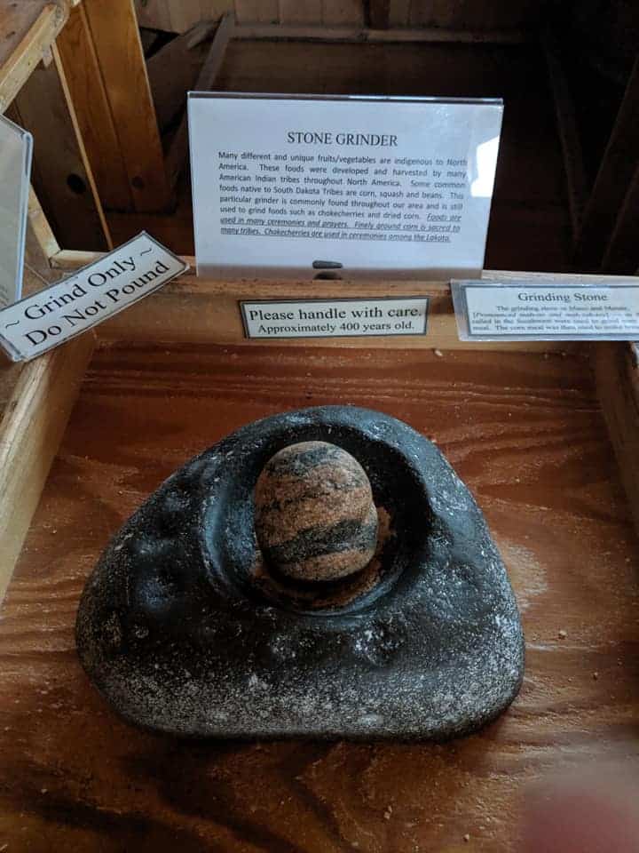 Close up of an old fashioned stone grinder and a sign that describes it and states that it is 400 years old.