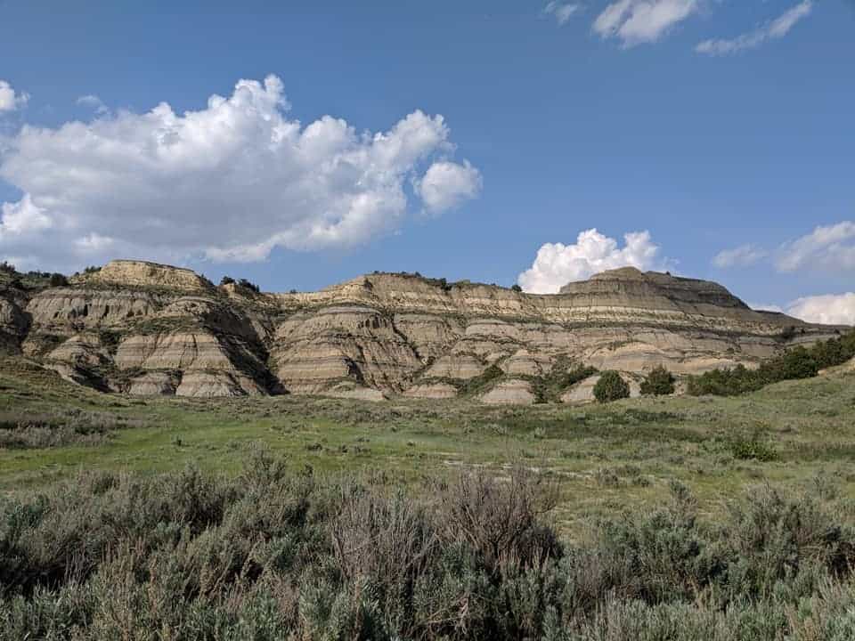 Mountain scenery- Mountains in the distance have lines of colors. There is a grass field in between camera and mountains