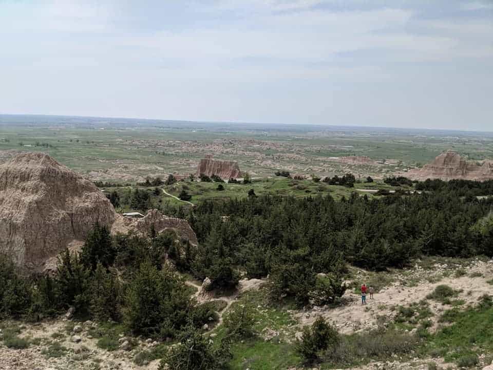 View from the top of Notch trail. There are trees, patches of grass and  the Black Hills as far as the eye can see.