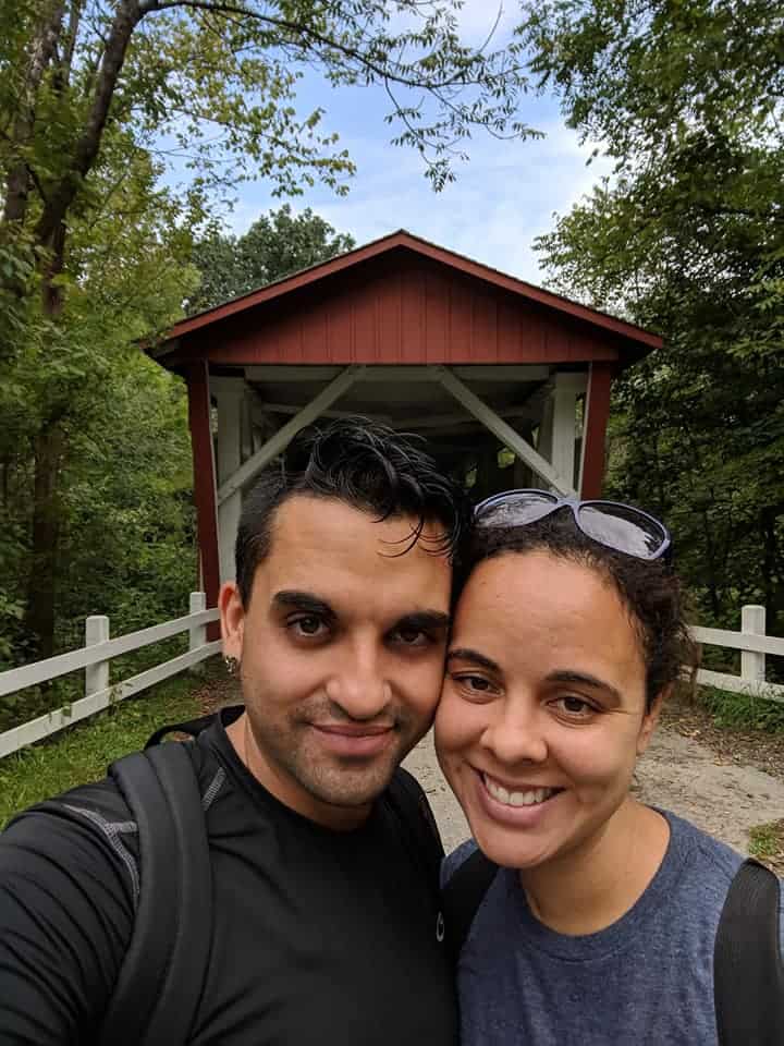 Man and Woman smiling in front of Everett Covered Bridge (red)