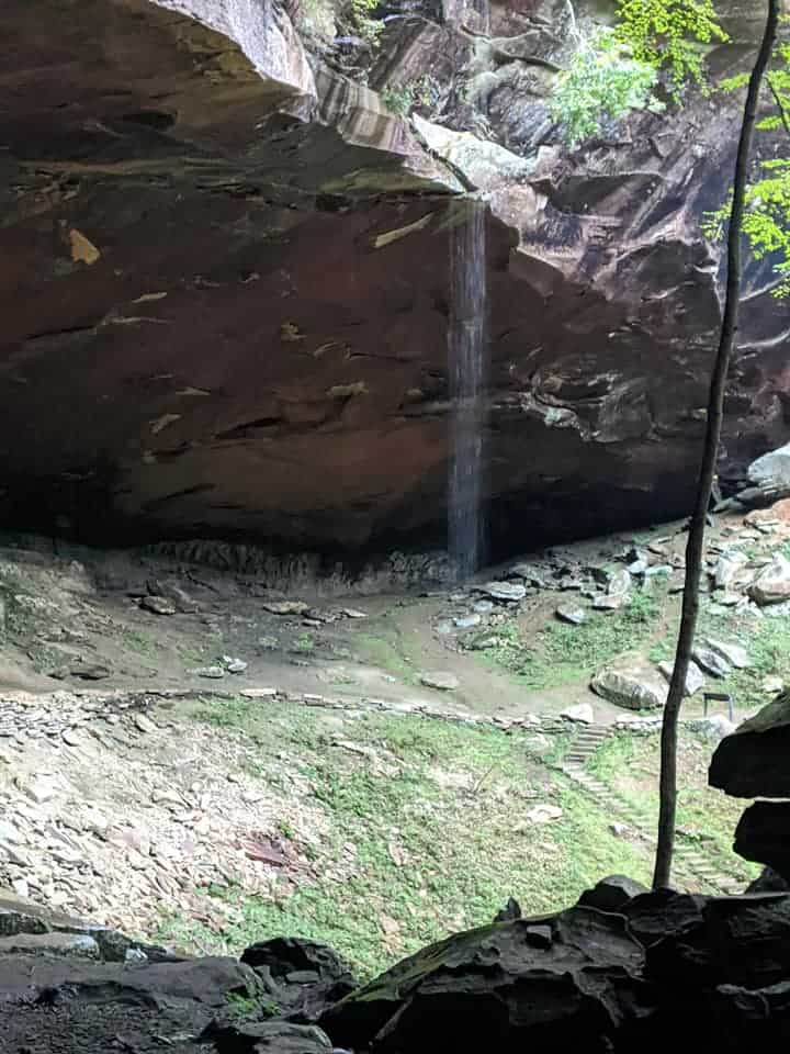 View of Yahoo Falls located in Kentucky. The water is falling from a large rock area. You can see the falls until the view is blocked by the rocks on the path we were on.