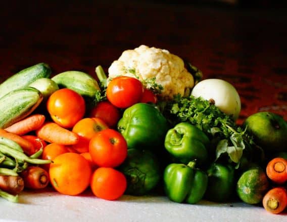 Artful display of vegetables such as carrots, zucchini, tomatoes, green pepper and cauliflower stacked on top of each other in a pyramid type shape.