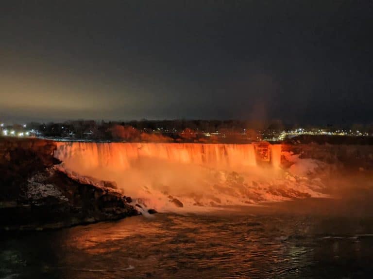 Niagara Falls lit up orange at night.
