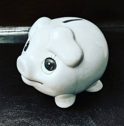 Blue piggy bank sitting on a black background.