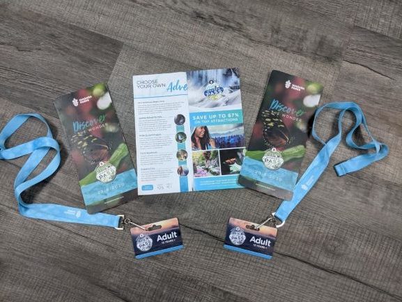 2 wonder passes on light blue lanyards displayed with 3 brochures for Niagara Falls attractions with the middle one open.