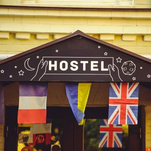 Building with a Hostel sign on it and multiple flags from other countries below  the sign.