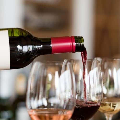 Bottle of red wine being poured into a wine glass