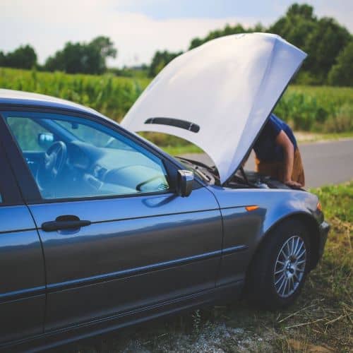 A person checking under the hood of their car