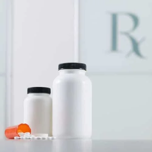2 medicine bottles standing up, one bottle on the side with pills spilling out of it