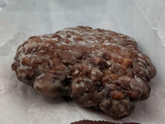 Close up of an apple fritter inside a white bag