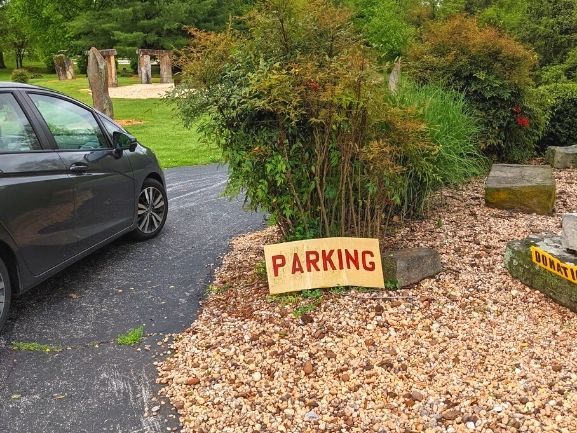 Sign in a driveway directing visitors on where to park for Kentucky's Stonehenge and a small donation box