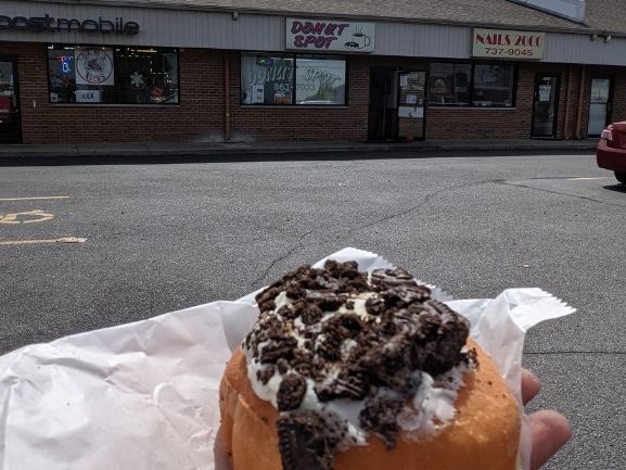 Oreo donut that has white frosting and oreo pieces on top.