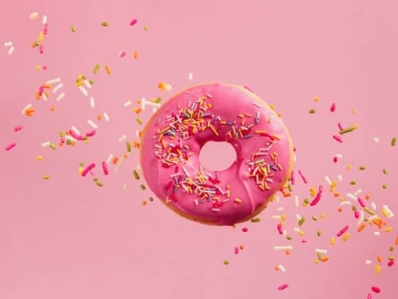 Pink frosted donut with sprinkles all around it