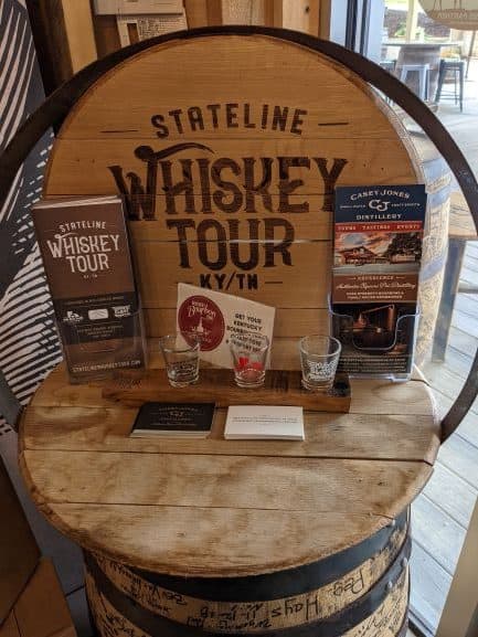 Display for the Stateline Whiskey Tour. It is set up on a barrel and has pamphlets and shot glasses on it.