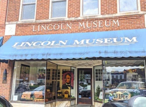 Front of the Lincoln Museum building. There is a blue awning and the front windows display photos of President Lincoln. It's a brick building.