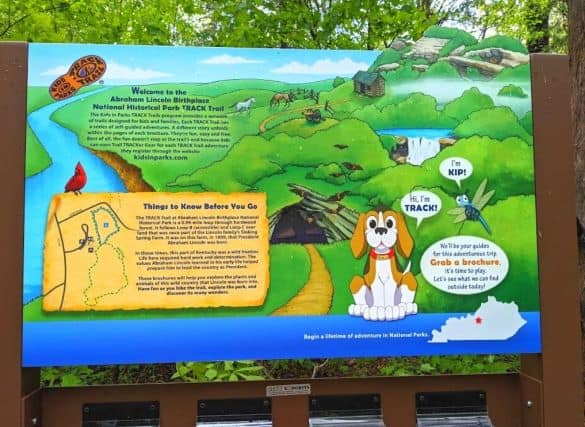 Large colorful sign advertising brochures for the Kids in Parks Track Trail. Track is a brown and white cartoon dog.