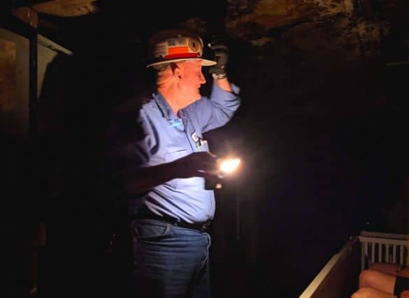 Mine tour guide in the dark lit up by a gas lamp