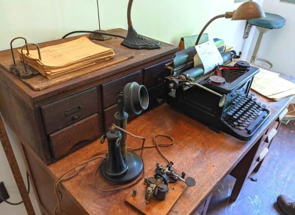 An old fashioned phone and a typewriter on an old wooden desk