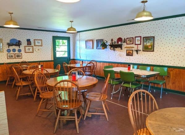 An old-fashioned room full of wooden tables and chairs. The bottom half of the walls are wood paneling