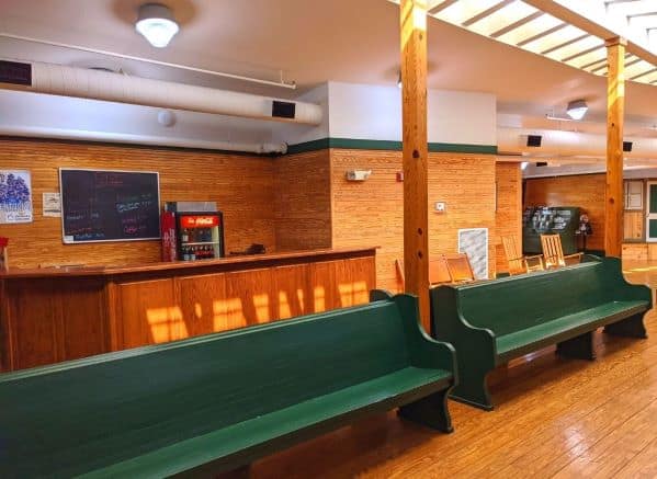 The seating area inside the Welcome Center; Benches are green. The walls and floor are wood