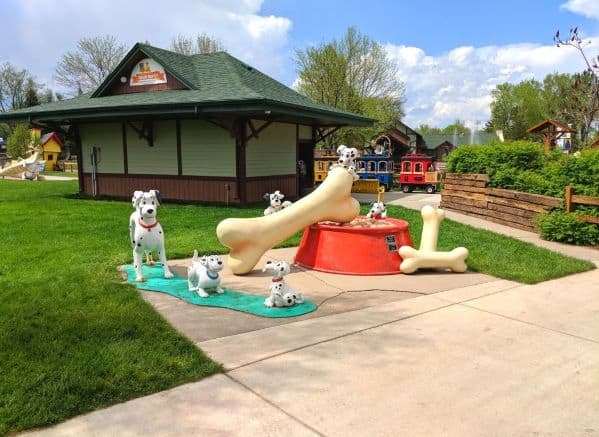Dalmatian statues from 101 Dalmatians playing around a large dog bowl and three bones. This is at Storybook Island  