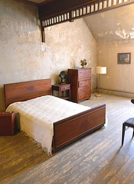 Room where several scenes of the Shawshank Redemption were filmed. There is a bed, dresser, side table, and suitcase