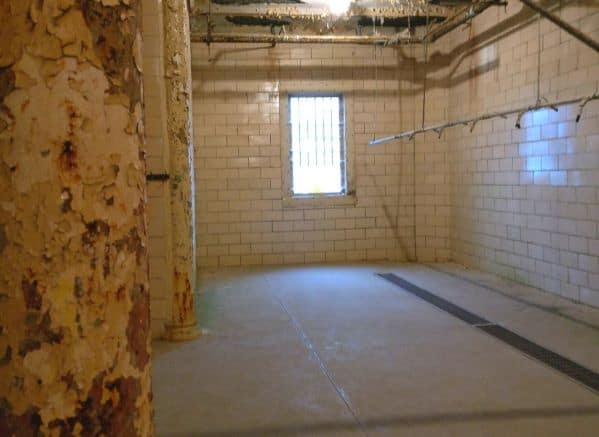 Shower room in Ohio State Reformatory. Walls are tile and there are two cylinder columns that are peeling paint