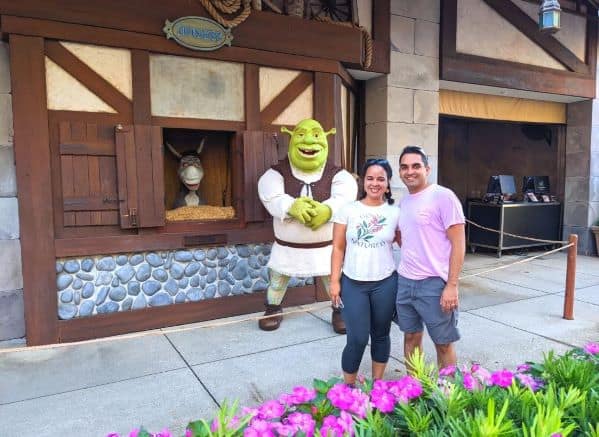 Couple posing with Shrek and Donkey in front of a cottage façade at Universal Studios