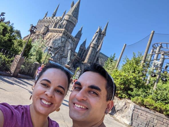 Couple smiling in front of Hogwarts Castle