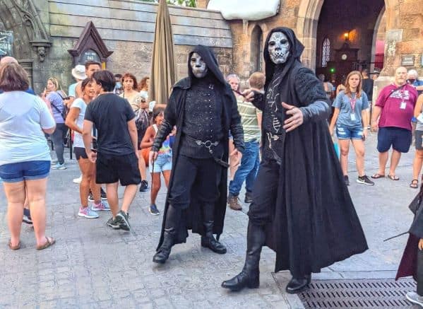 2 Death Eaters standing together in a crowd at Universal. They are dressed in black and posing with their wands