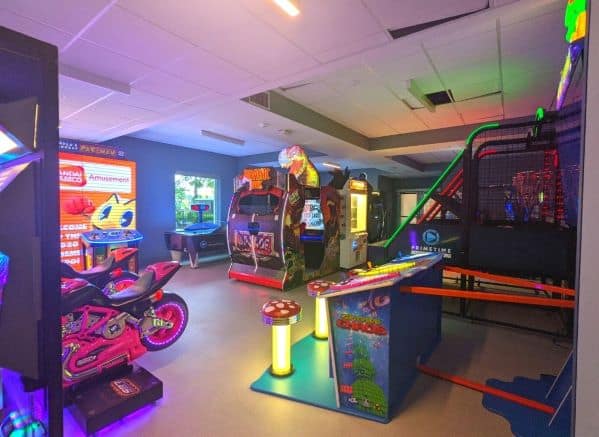Several arcade games, a basketball hoop game, and motorcycle riding game inside the game room at Dockside Inn