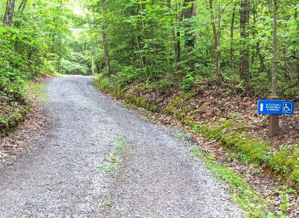 gravel path next to a sign that says wheelchair accessible. It has an arrow pointing ahead to the wheelchair accessible path at Beartown State Park