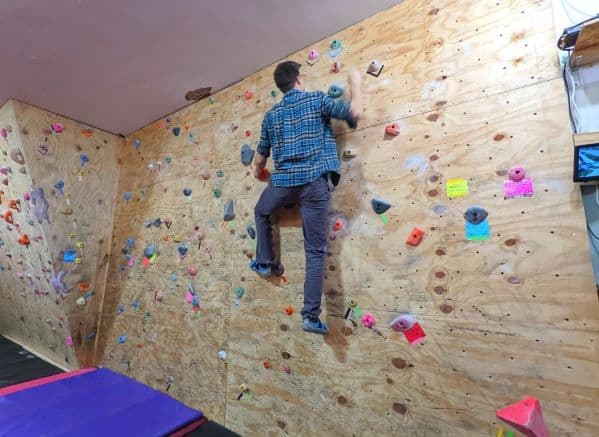 Man wearing blue shirt rock climbing on a wall