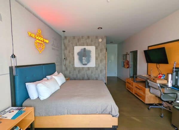 King Room at DogHouse Hotel. There is a guitar, king bed, TV and a beer tap in view.