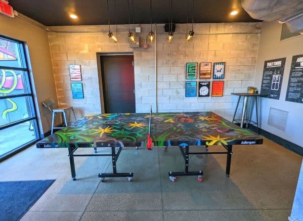 Spray painted Ping Pong table in the DogHouse Hotel. Table is strewn graffiti art with a variety of colors and images. 