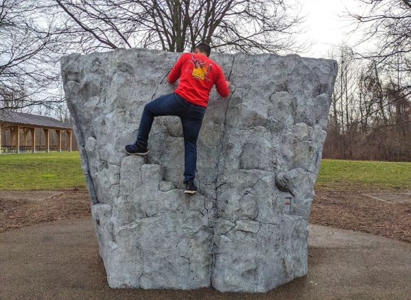 man climbing bouldering rock at Wildwood metro park