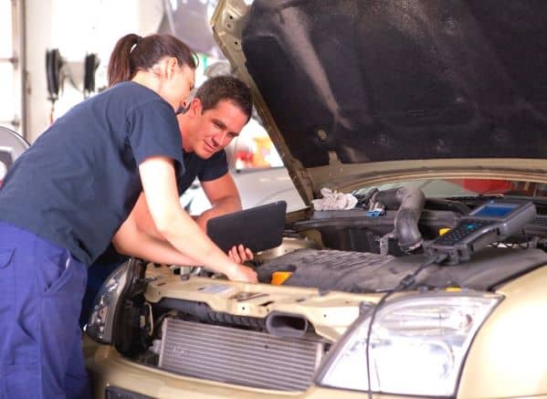 2 people  working on car engine
