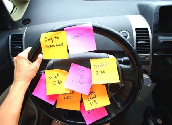 Steering wheel covered with post it notes that have errands written on them