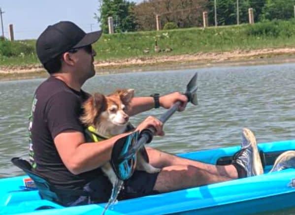 Man with small dog in lap while kayaking
