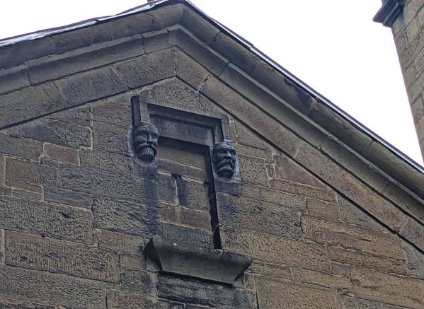 2 stone heads mounted on a historical brick building