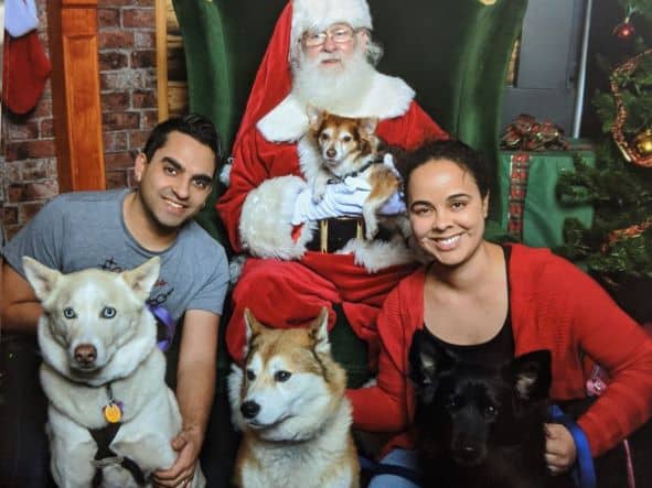 Couple with 2 dogs posing with santa in Santa's workshop