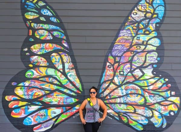 Woman standing in front of butterfly wing mural