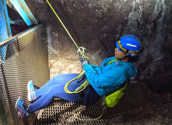 Woman on a small practice rappelling system in a mine