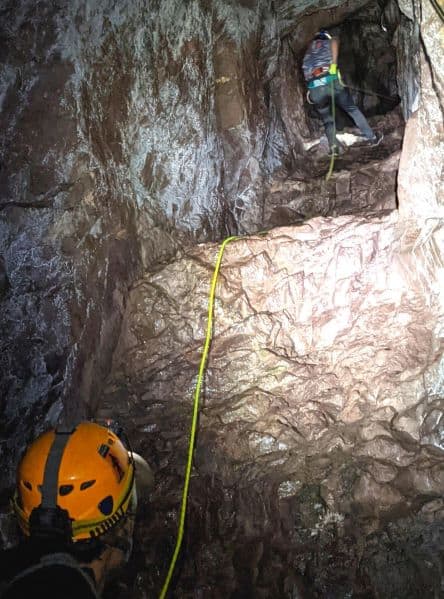 Woman rappelling 80ft down into a copper mine with a spotter