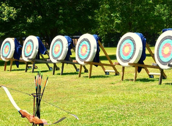 bow and arrows in a stand in front of static targets set up outside