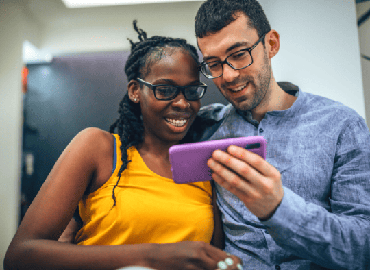 2 people smiling and staring at phone