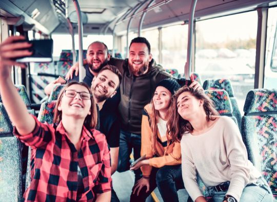 group of friends taking a selfie in a bus