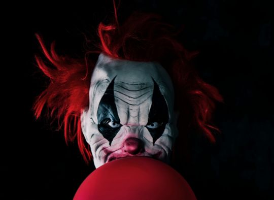 scary clown with red balloon